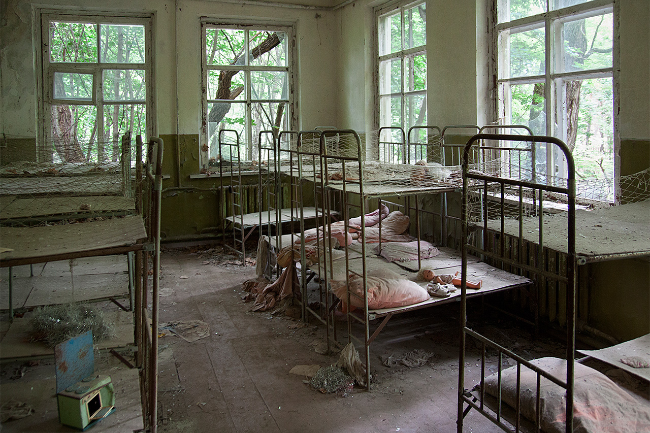 Abandoned kindergarten dormitory with rusted bunk beds and a doll in Pripyat