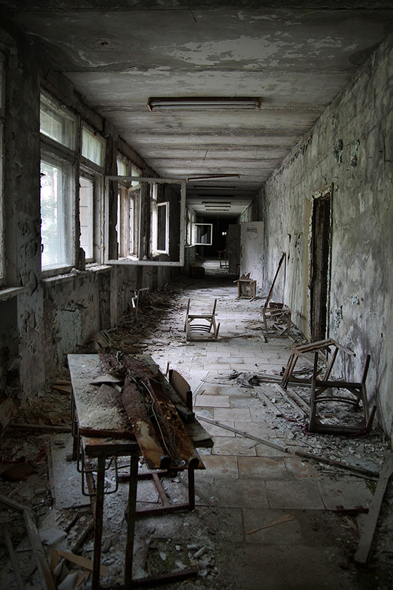 Abandoned school corridor with overturned chairs and desks in Pripyat
