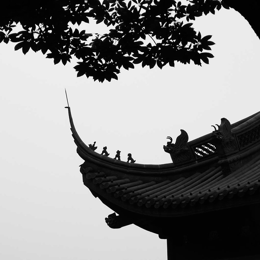 Silhouette of an upturned temple roof with dragon finials and leaves