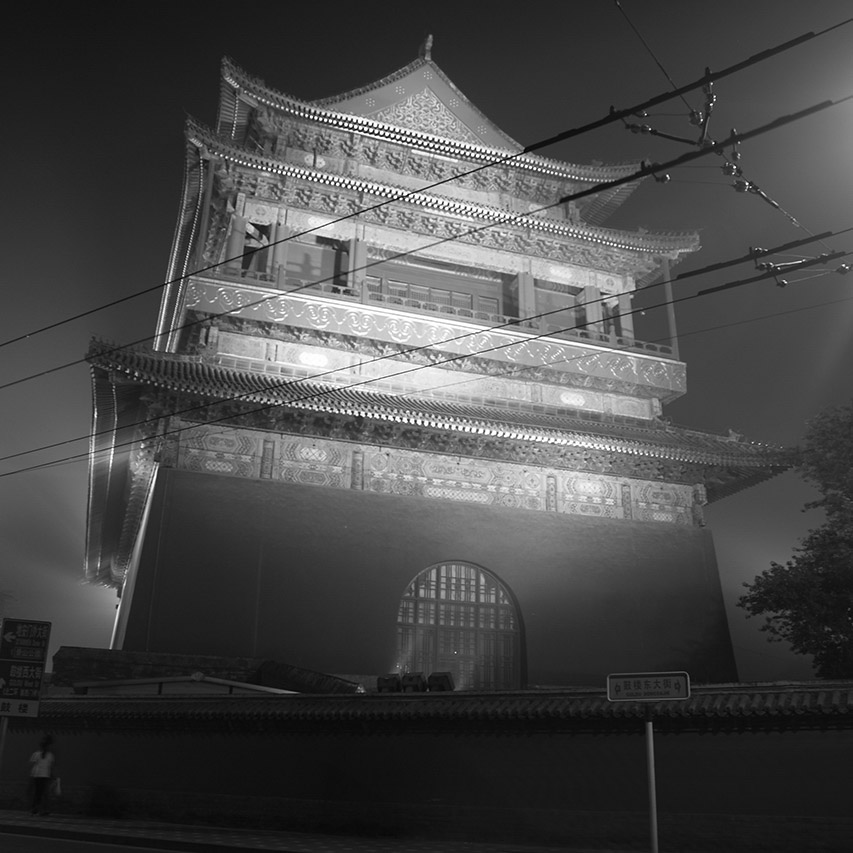 Xi'an Drum Tower illuminated at night through mist and wires