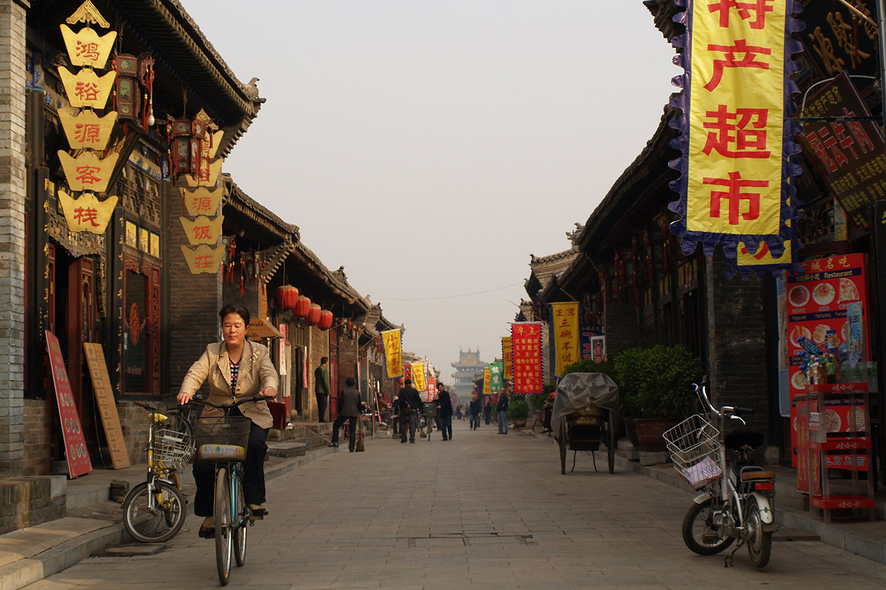 Woman cycling down a lantern-lined street in Pingyao old town