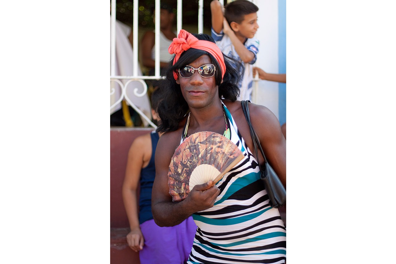 Portrait of a person with a red headscarf holding a fan in Trinidad, Cuba
