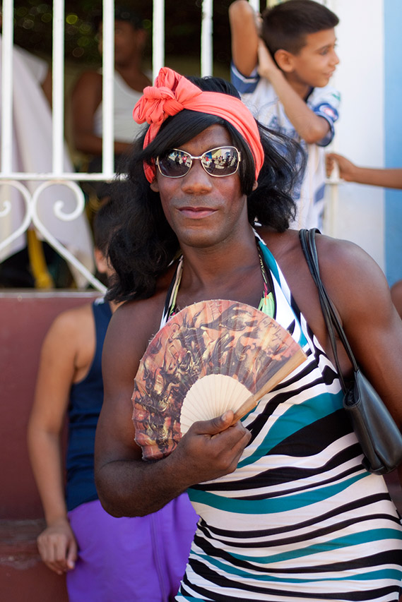 Portrait of a person with a red headscarf holding a fan in Trinidad, Cuba