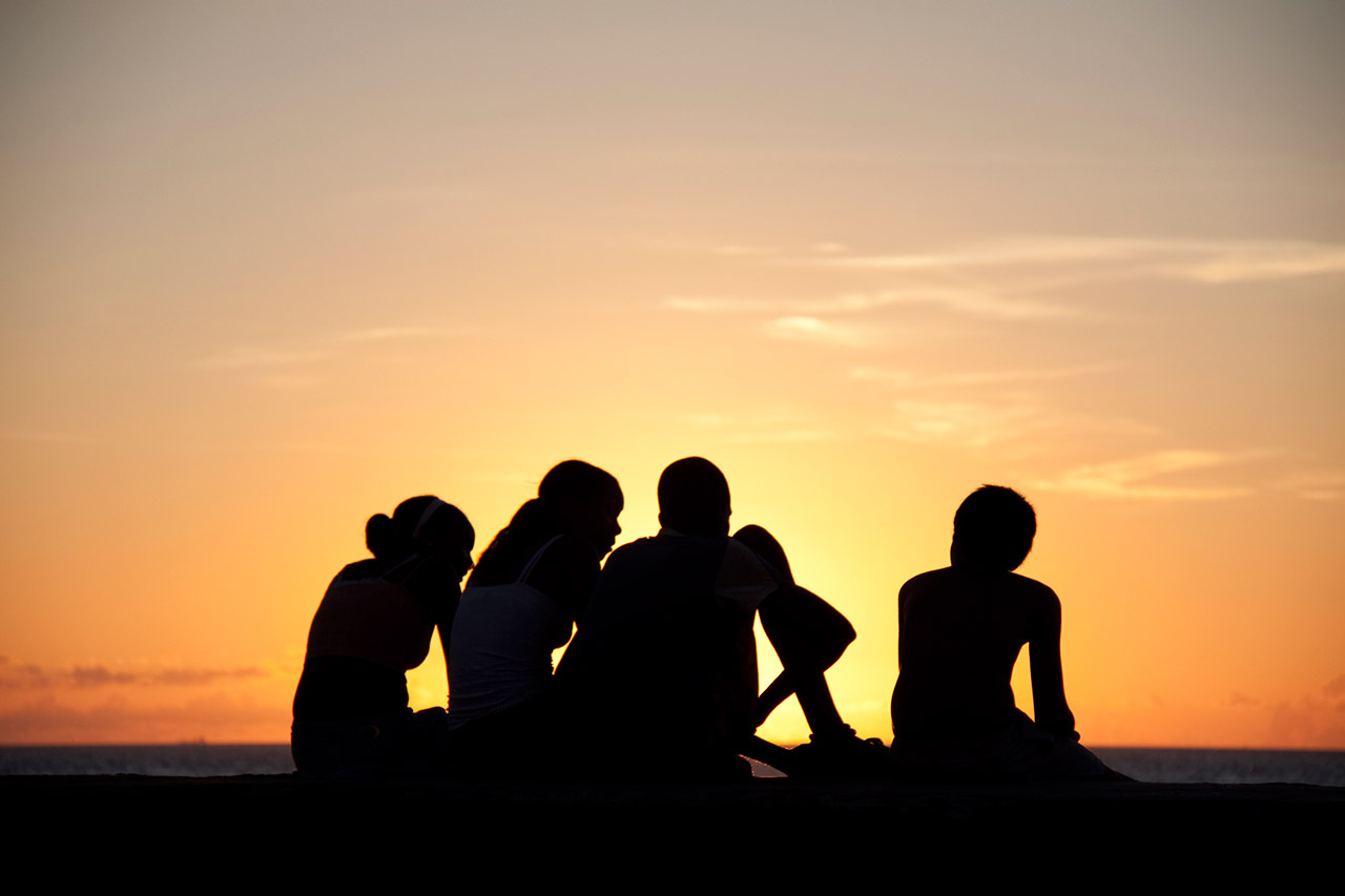 Silhouettes of youths sitting on the Malecón at sunset, Havana