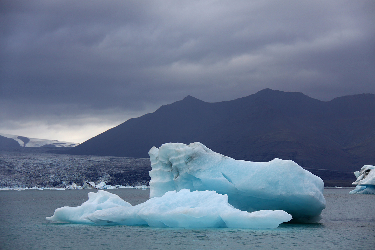 Blue iceberg in Jökulsárlón lagoon under cloudy sky