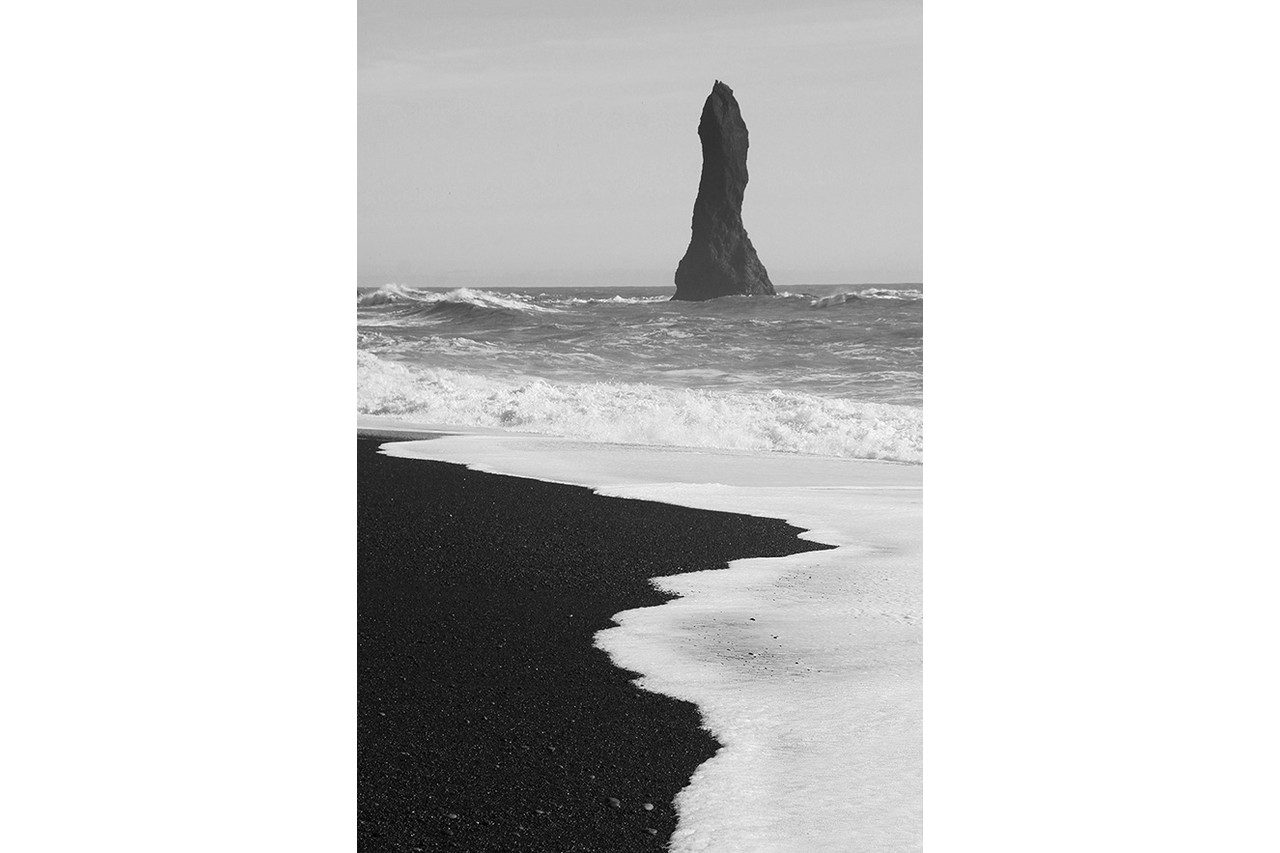 Lone basalt sea stack rising from the waves at Reynisfjara black sand beach