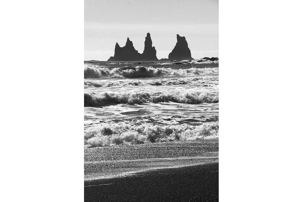 Reynisdrangar sea stacks silhouetted against crashing Atlantic waves at Reynisfjara