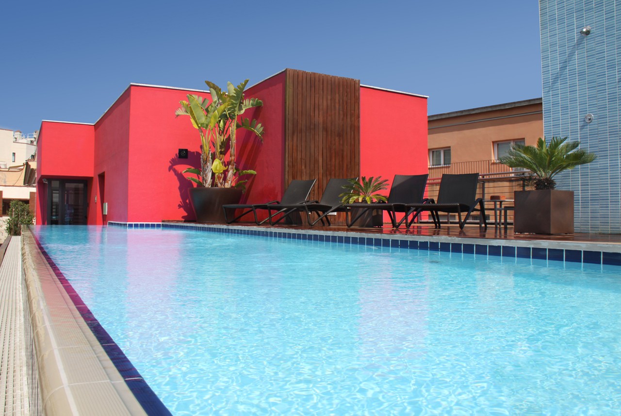 Rooftop pool with sun loungers and tropical plants at Hotel Catedral Barcelona