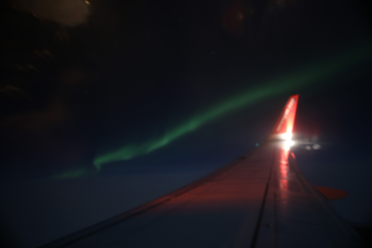 Northern lights seen from an airplane wing over the Arctic