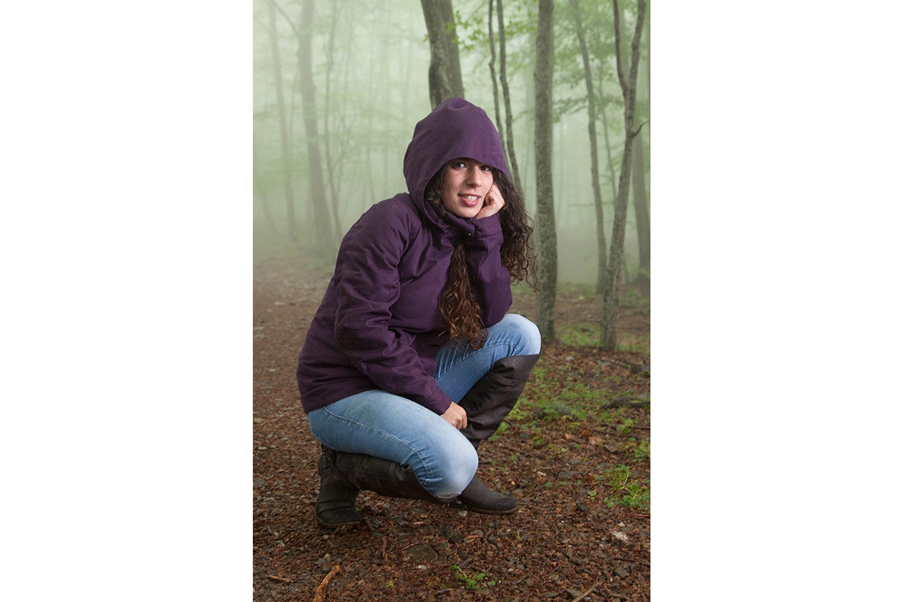 Woman with hood crouching in misty forest — Momawo