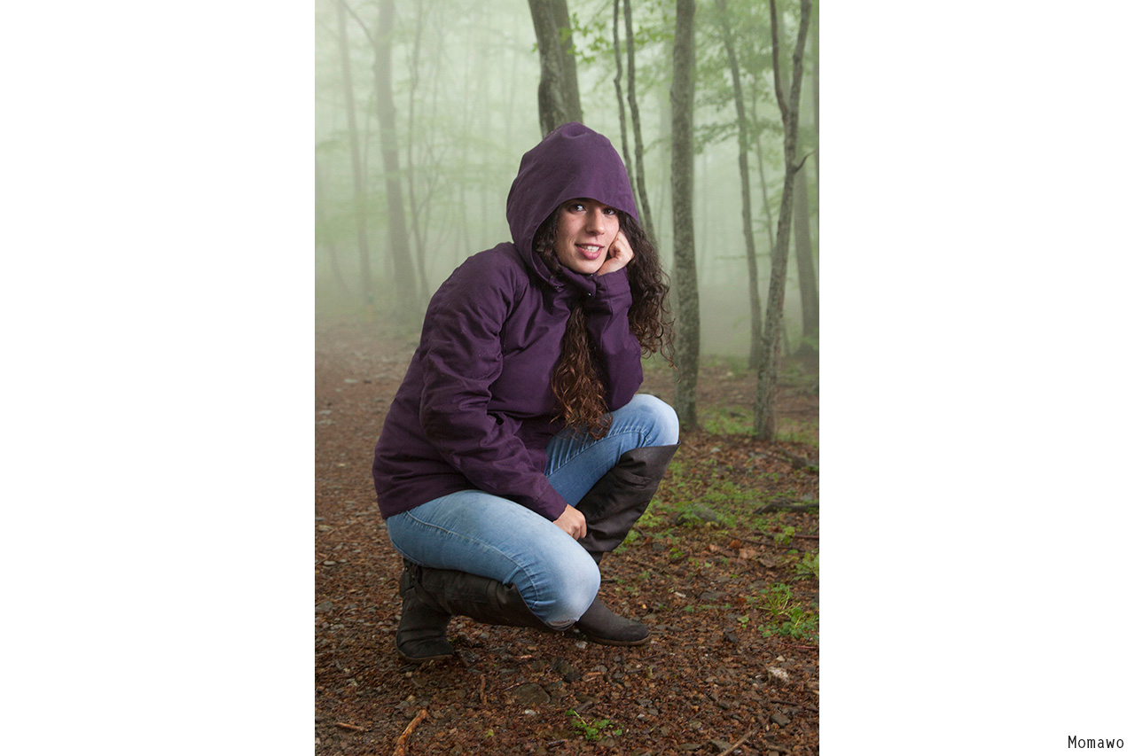 Woman with hood crouching in misty forest