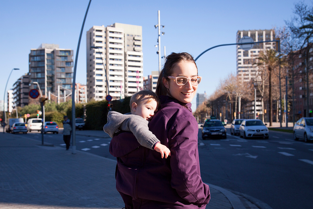Mother carrying child on her back in the city