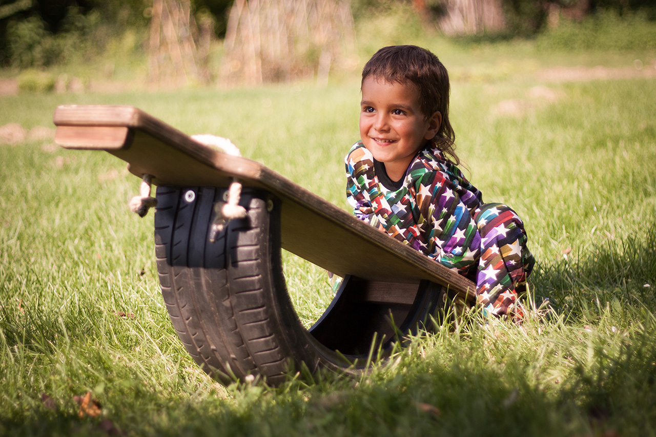 Smiling child on tire seesaw in grass
