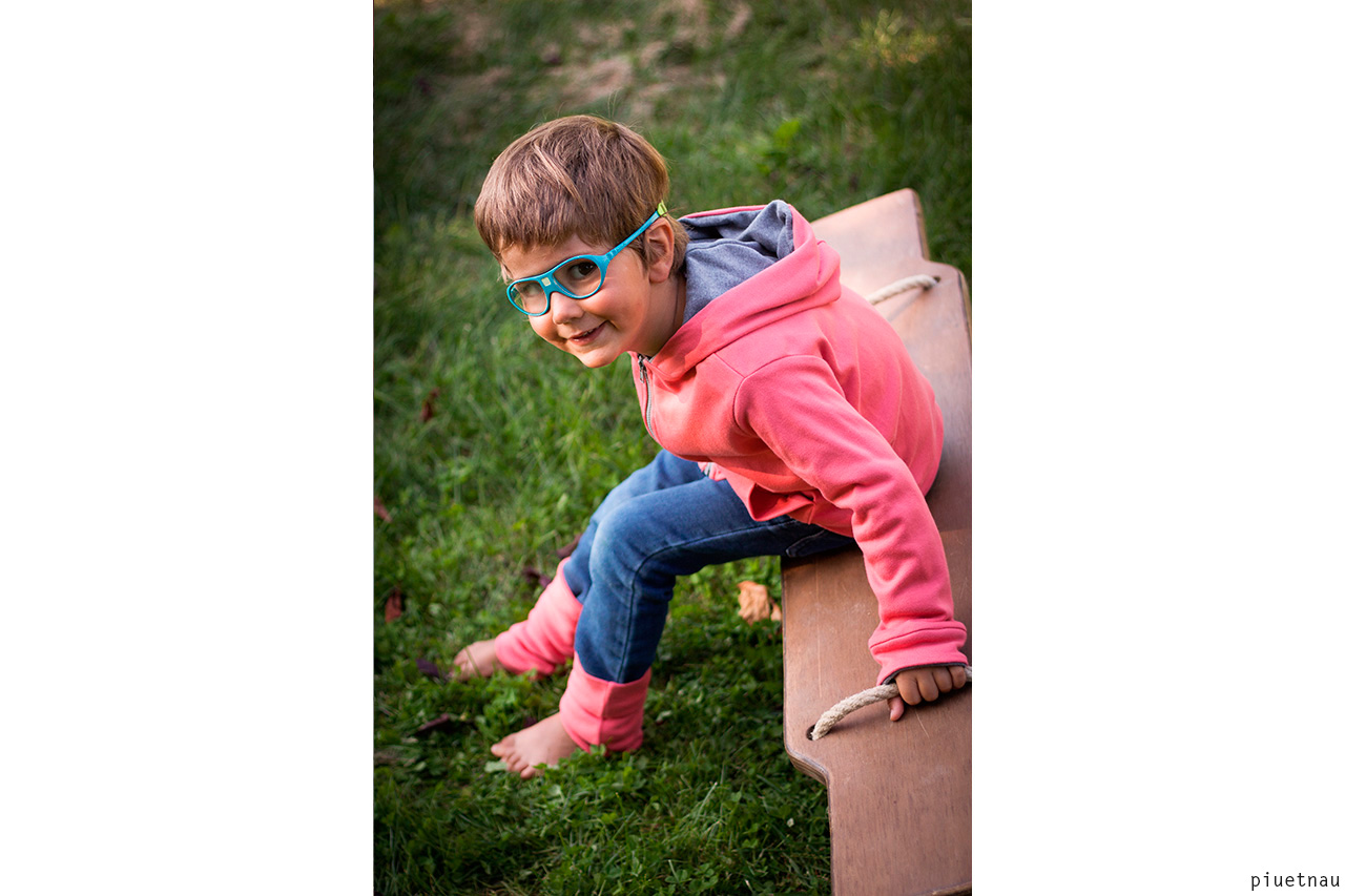 Child with blue glasses on wooden bench