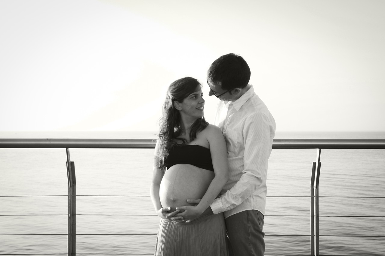 Black and white maternity portrait of a couple by the sea