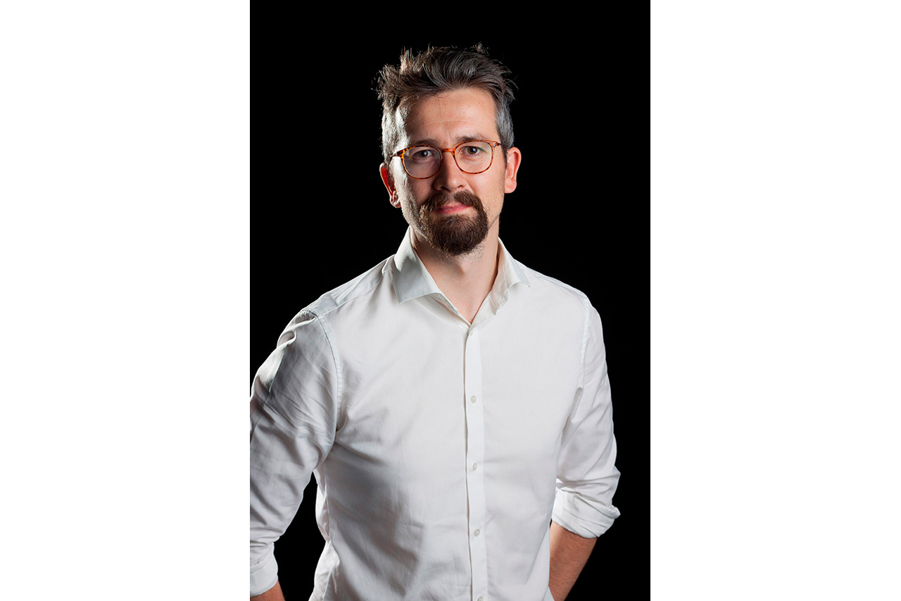 Studio portrait of man with beard and glasses on black background