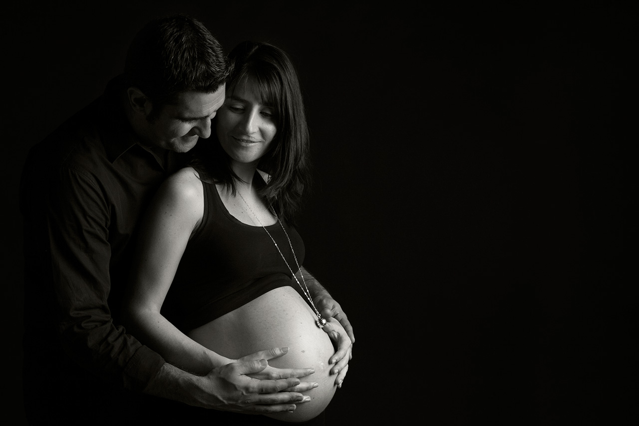 Black and white studio portrait of pregnant couple