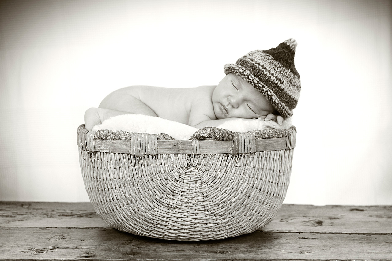 Newborn baby sleeping in basket with knit hat