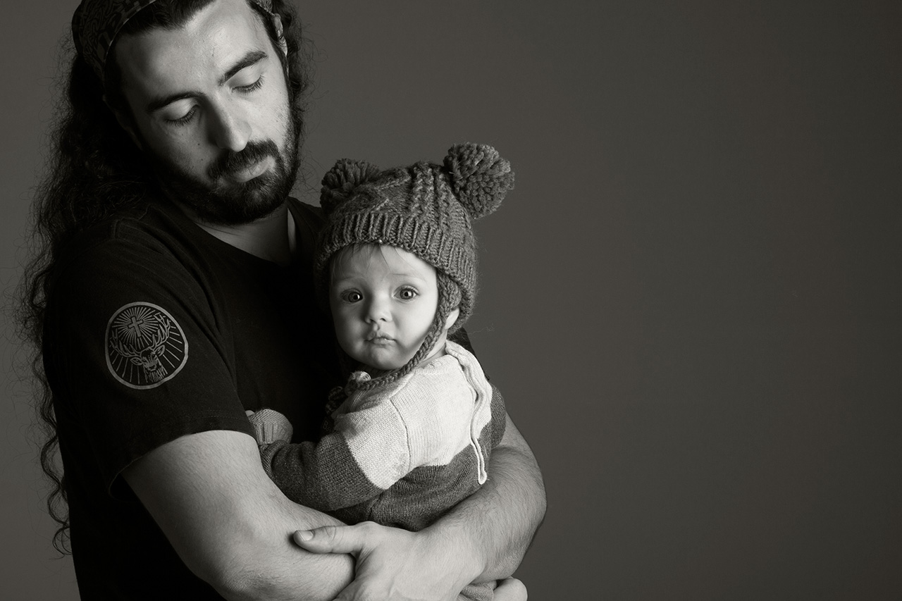 Black and white studio portrait of father holding baby