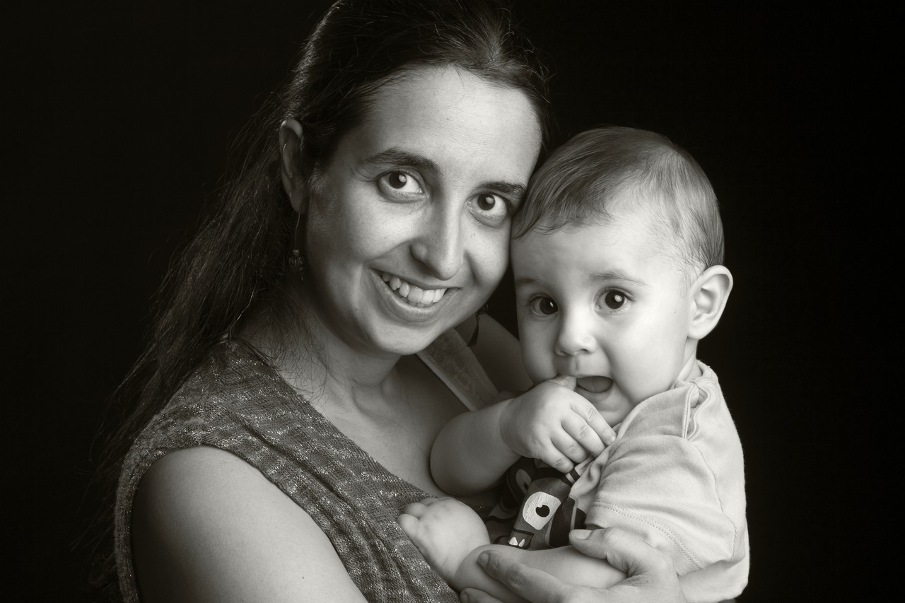 Black and white studio portrait of father playing with baby on the floor
