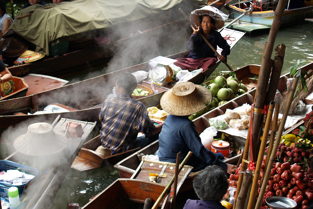 Steam rising over vendors in conical hats at Damnoen Saduak floating market
