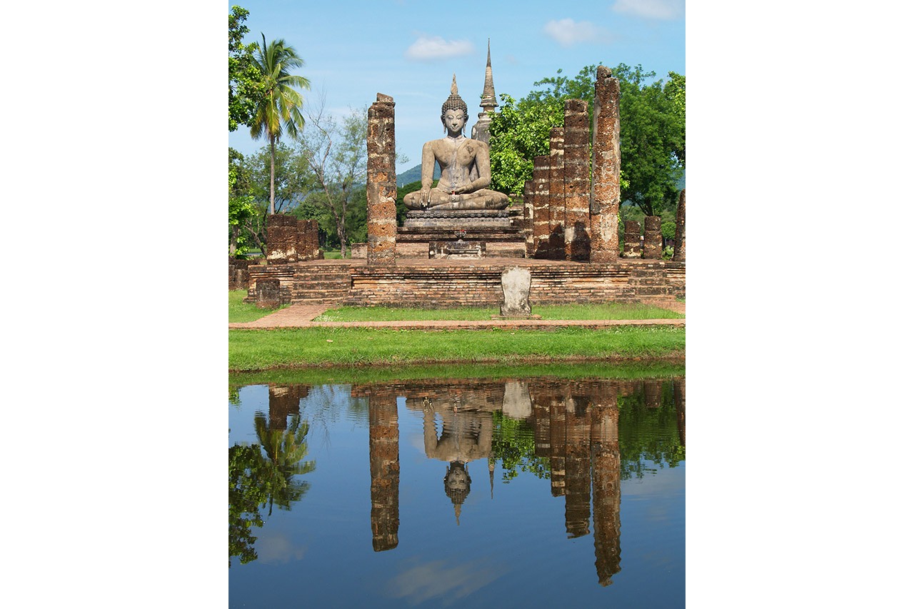 Seated Buddha reflected in a pond at Sukhothai historical park