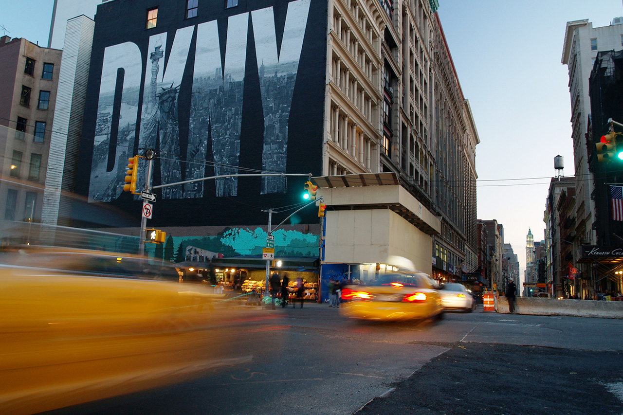 DKNY mural with yellow taxis in Manhattan at dusk