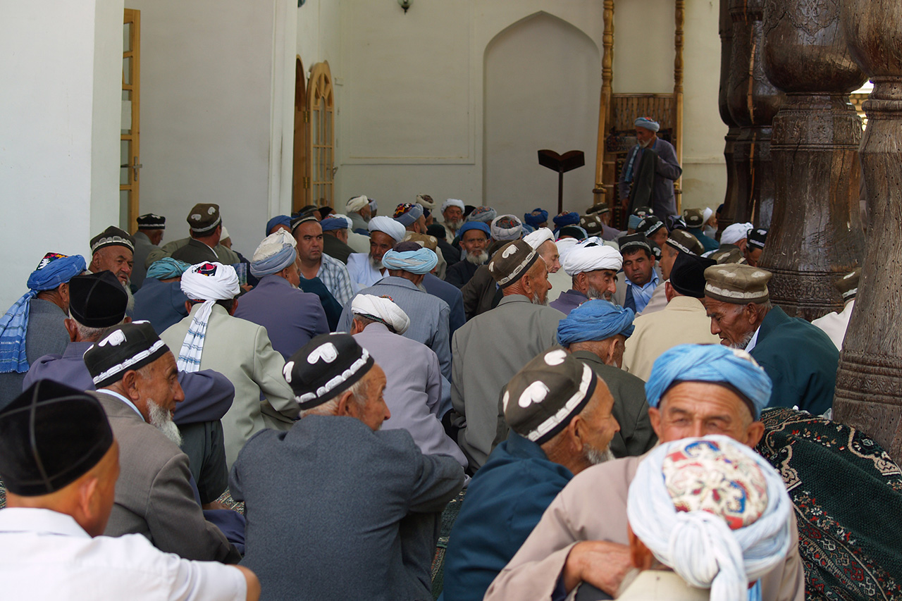 Uzbek elders in traditional doppa hats gathered inside a mosque