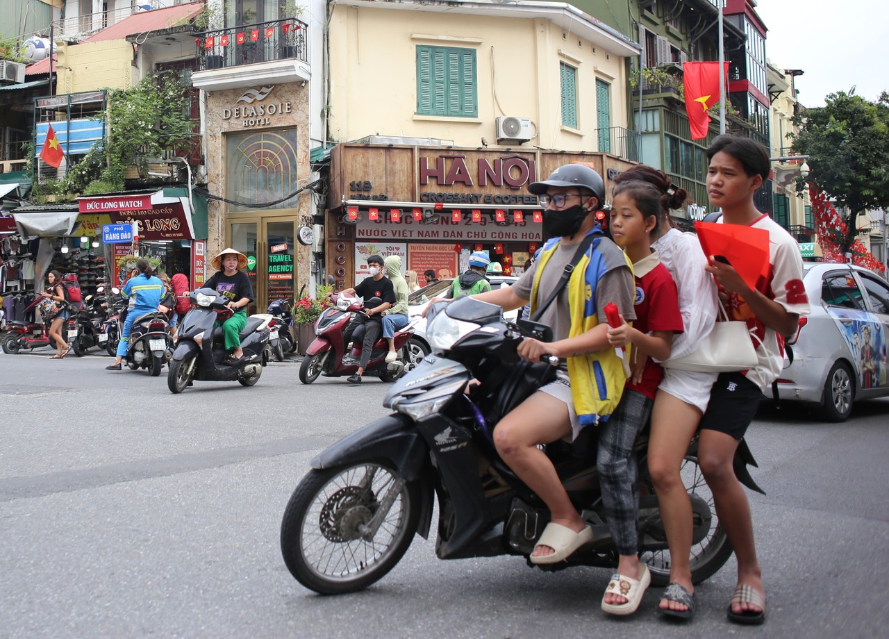 Family of four on a motorbike waiting at a corner of Hanoi's Old Quarter