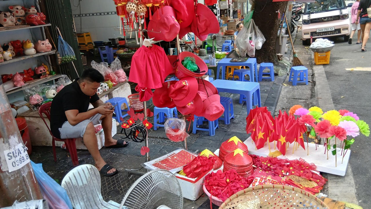 Street stall selling red Vietnamese flags, hats and paper flowers in Hanoi