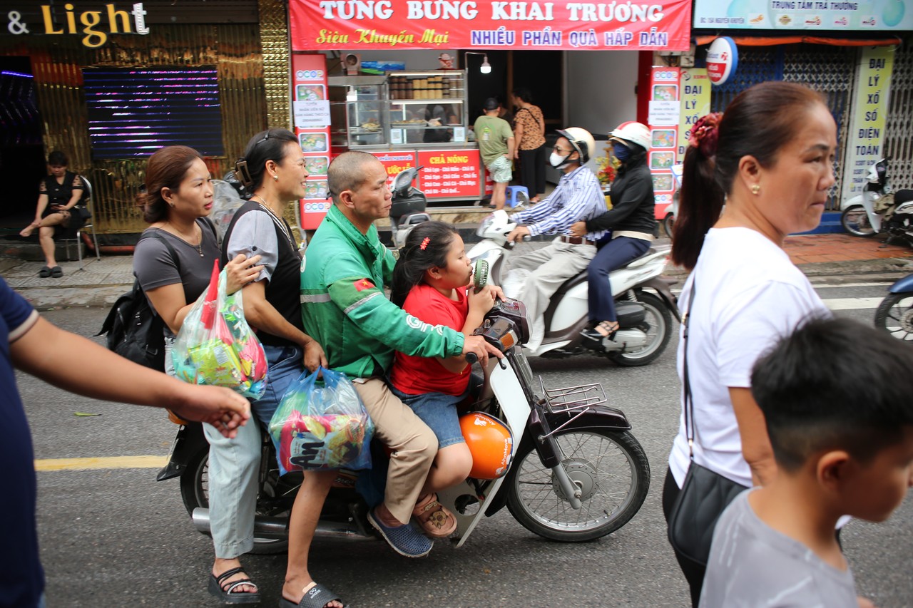 Crowded Hanoi street with a family and shopping bags on a motorbike